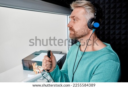 Hearing test for adult man. Handsome mature male during hearing exam and audiometry sitting in audiology booth at hearing clinic