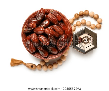Bowl of dates, prayer beads and Muslim lantern for Ramadan on white background Royalty-Free Stock Photo #2255589293