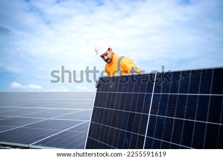 Installing solar power plant as sustainable energy source. Worker placing solar panel on the roof. Royalty-Free Stock Photo #2255591619