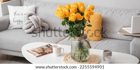 Yellow roses in vase on table in living room