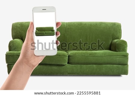 Woman with mobile phone buying online new sofa in furniture store