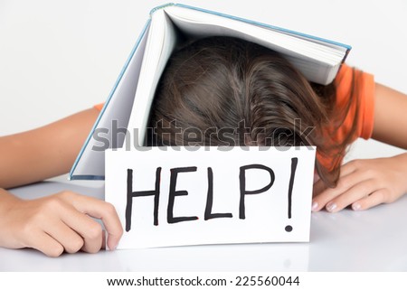 Girl sleeping with a textbook over her head and holding a sign with the word Help!