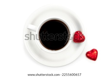 Cup of coffee and heart shaped chocolates on a white background, flat lay.