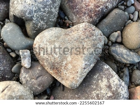 A heart of stone among other stones with petroglyphs in the background.  symbol of love.

 image formats