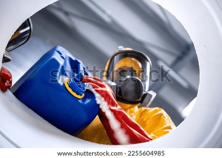 Bottom view of factory worker in protection hazmat suit and gas mask pouring chemicals into barrel in production factory. Royalty-Free Stock Photo #2255604985