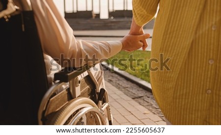 Man with reduced mobility holding wife's hand, support in relationship, love Royalty-Free Stock Photo #2255605637