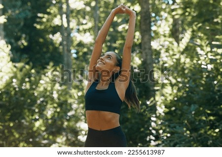 Portrait of a fit smiling young girl breathing deeply during yoga in the woods Royalty-Free Stock Photo #2255613987