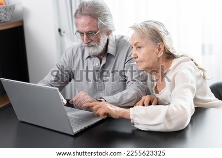 Older caucasian couple with tablet computer in living room at home