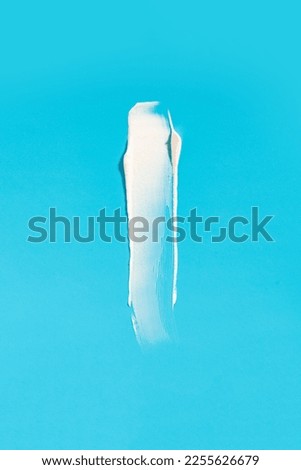 White cream smear on a blue background. Vertical photography. 