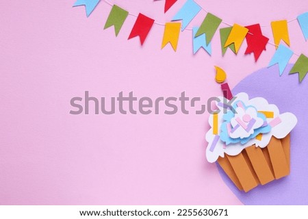 Birthday party. Colorful bunting flags and paper cupcake on pink background, flat lay. Space for text