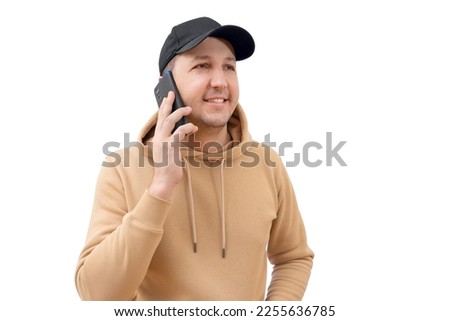 Young happy man in a sweatshirt and cap using a mobile phone on a white background. People lifestyle concept