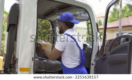Black employee worker with a truck car moving house for customers, delivering boxes with uniform. Vehicle transportation. Shipping and packaging business occupation service company. People lifestyle.