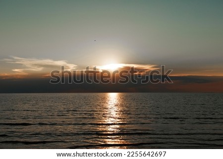 Waves on the sea during sunset. Relaxation, enjoyment. Journey to the ocean, peace and happiness. Colorful, bright, orange sunset. The sun shines through the clouds on the ocean. Beautiful wallpapers