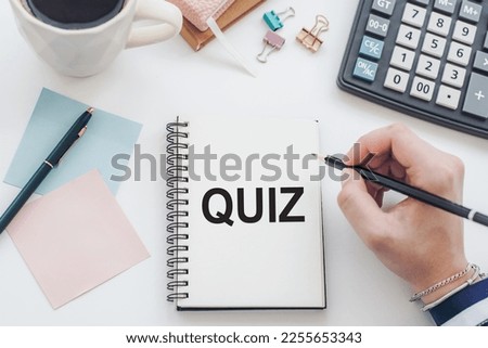 On an office table is a notebook with the handwritten text QUIZ and cup of coffee, pen and calculator. Business concept.