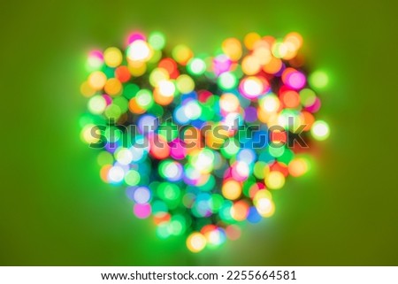 Heart shape made of multi-colored circles of lights on bright green background. Flat lay background for Valentines Day Royalty-Free Stock Photo #2255664581