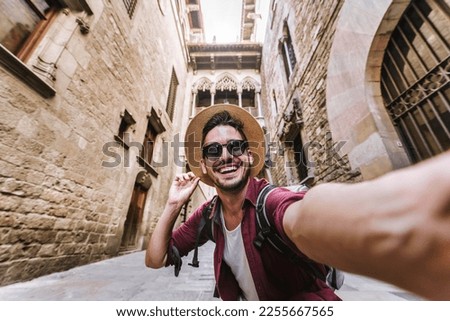 Happy male tourist taking selfie picture in front of Pont del Bisbe in Barcelona, Spain - Travel, technology and lifestyle concept