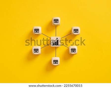 Business sales growth. Expanding franchise stores and increasing profitability concept. Wooden cubes with store and ascending graph symbols linked with each other with lines. Royalty-Free Stock Photo #2255670015