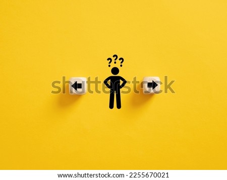 Decision making and choosing the right path. Confusion about deciding which direction to go. Stickman with question marks standing in between the wooden cubes with arrow symbols. Royalty-Free Stock Photo #2255670021