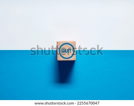 The word Quit on wooden cube push button on blue and white background. Decision to quit a job or smoking concept.