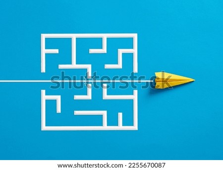 Overcoming the barriers. Conquering the obstacles. Way to success and business solutions. Exit strategy. Paper plane breaking through the maze on blue background. Royalty-Free Stock Photo #2255670087