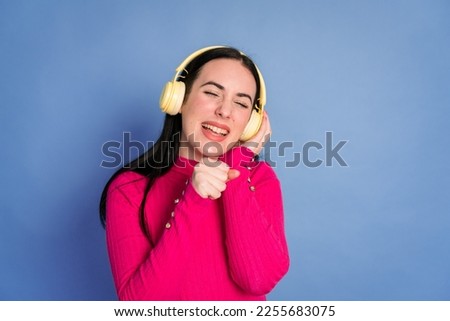 Smiling woman listening to music in headphones and singing