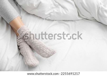 Woman wearing warm socks in comfortable bed, closeup. Space for text Royalty-Free Stock Photo #2255691217