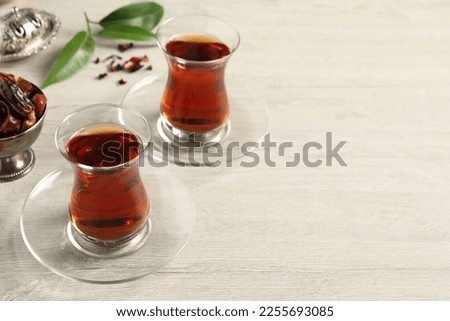 Glasses of tea and vintage tea set on wooden table, space for text