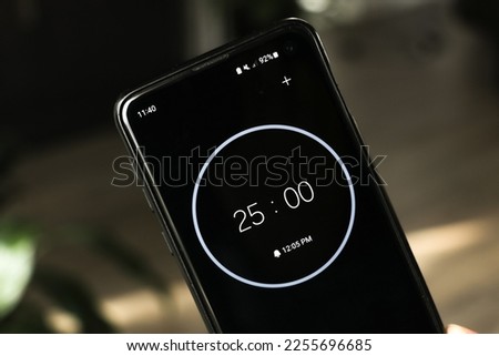 A phone with a black and white 25-minute timer to study with the pomodoro method on a blurry background Royalty-Free Stock Photo #2255696685