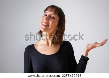 Portrait of a girl on white background. Brown short hair girl. Content girl showing flat hand as if holding something on top