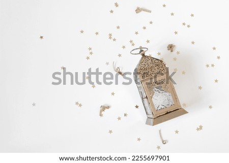 Festive Ramadan holiday composition, web banner. Golden ornamental Moroccan lantern and star shaped confetti isolated on white table background. Iftar party, Eid ul Fitr or Eid al Adha flatlay. Top. Royalty-Free Stock Photo #2255697901