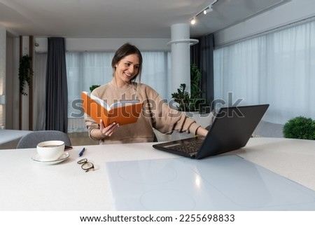 Young business woman attends online retraining course for more opportunities in progress to find a better job watching and listening to a lecture on laptop and taking notes of important informations Royalty-Free Stock Photo #2255698833