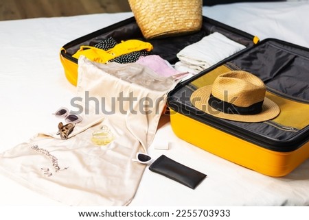 Suitcase scattered things for the trip: womens dress, perfume, straw hat, straw bag, sunglasses, swimsuit. Concept: vacation time, forward to travel. purchase of air tickets, preparation for vacation