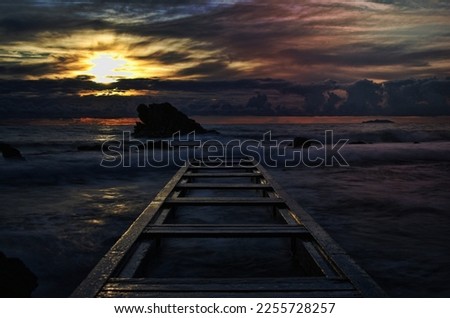sunset on a tuscany sea watching on a pier from the beach