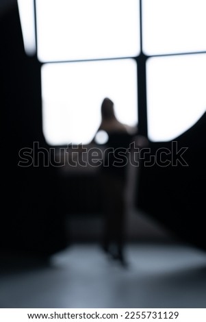Out of focus. A young and beautiful woman opens the curtains.
