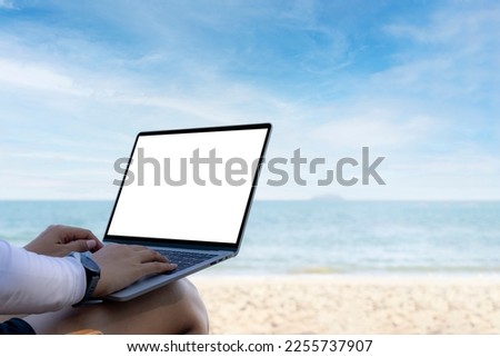 Hands using laptop computer with beautiful beach background