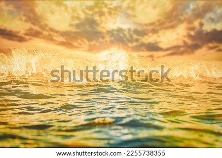 Bright background with sea water close-up in soft focus. Relaxing sunset sea view in orange tones. Dreams of pleasant relaxation by the sea during your holidays.