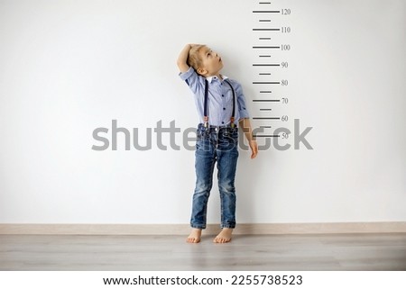 Little child, blond boy, measuring height against wall in room Royalty-Free Stock Photo #2255738523