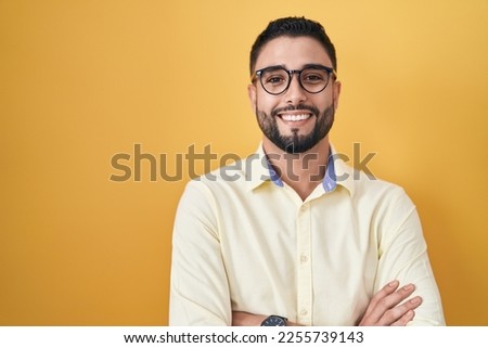Hispanic young man wearing business clothes and glasses happy face smiling with crossed arms looking at the camera. positive person.  Royalty-Free Stock Photo #2255739143