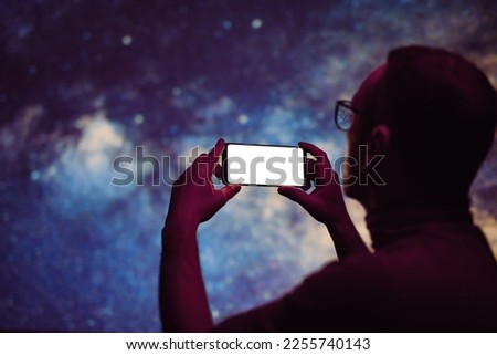 Astronomer photographing Milky Way night sky with a modern smartphone.