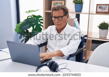 Middle age man sitting on wheelchair teleworking at home