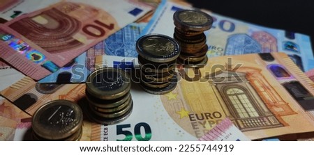 Close-up view of euro coins stacked in a column on euro banknotes, details on the coin, photo