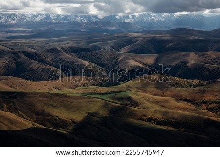 Landscape photo of a scenic view on the Caucasian Ridge from the plateau Bermamyt cloudy sky and shining sun.