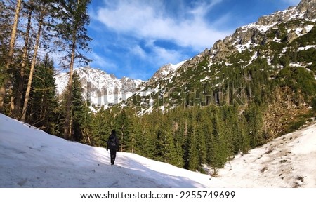 Beautiful panorama in winter Tatry mountains, Five Lakes Valley, Dolina Pieciu Stawow with young pretty woman trekking alone, crampon shoes. Phone photo