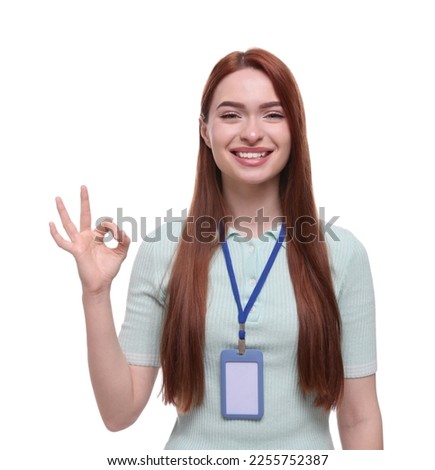 Happy woman with VIP pass badge showing OK gesture on white background