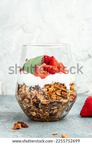 Parfait with yogurt, granola, jam, fresh berries and mint leaves in glass jar. gluten free diet, Healthy breakfast. vertical image. place for text.