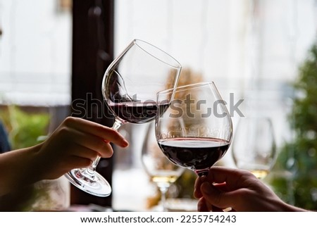 Close up of hands young couple clinking with glasses of red wine at restaurant Royalty-Free Stock Photo #2255754243
