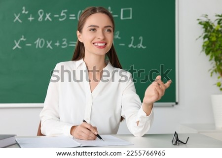 Young math’s teacher giving lesson at table in classroom