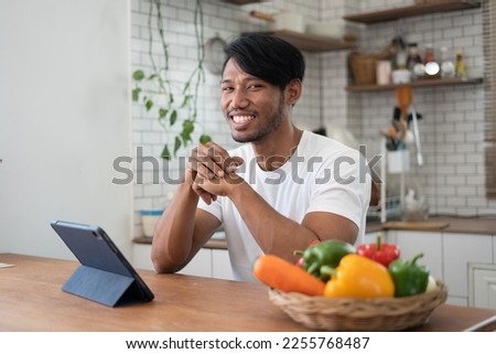 Handsome asian man cooking at home preparing salad in kitchen.