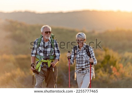 Active senior Caucasian couple hiking in mountains with backpacks and hiking poles, enjoying their adventure Royalty-Free Stock Photo #2255777465