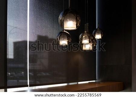Roller blinds in the cafe. Solar shades black color in the urban style interior. Wooden table near the window and bar stools are along it. Screen material for automated roller blinds. Selective fokus. Royalty-Free Stock Photo #2255785569